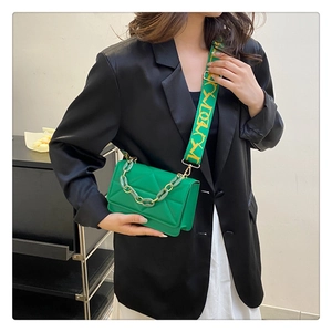 Detail of emerald green quilted crossbody bag with chunky resin chain and wide woven strap