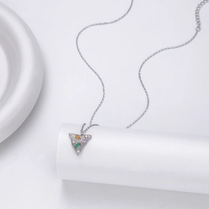 Macro shot of silver triangle pendant set with green, yellow, purple, and white gemstones