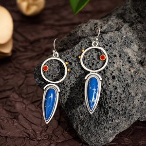 Close-up of bohemian lapis lazuli drop earrings resting on black volcanic stone