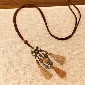 Detailed close-up of retro bohemian tassel necklace with wooden beads and floral charm