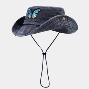 Détail du chapeau de cowboy en denim bleu avec broderie papillon et jugulaire