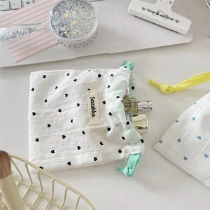 Detail of white cotton drawstring pouch with black heart prints and woven green cords