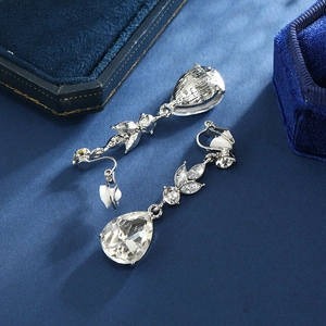 Macro detail of silver bridal clip-on earrings with teardrop crystal on blue velvet