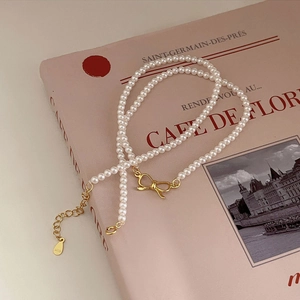 925 silver pearl necklace with gold bow pendant on a French aesthetic magazine background