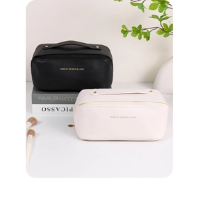 Close-up of minimalist PU leather makeup bags with handles in black and cream