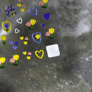 Macro shot of 5D embossed nail stickers featuring colorful tulips and hearts detail