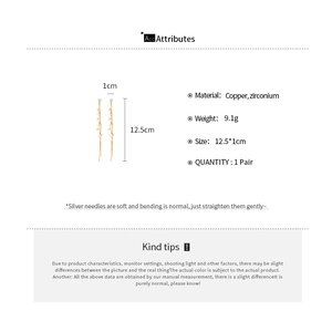 Vue détaillée des boucles d'oreilles longues à pompons dorés avec zircon et argent