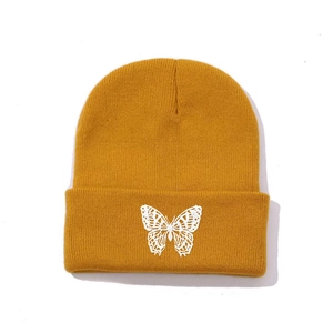 Detailed close-up of white butterfly embroidery on a yellow ribbed knit beanie cuff