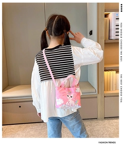 Pink canvas kids messenger bag with unicorn print worn by a child in a room