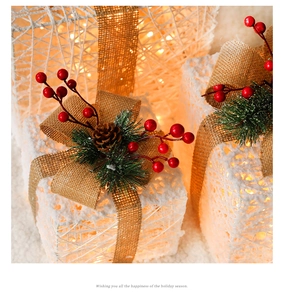 Detail of lighted Christmas gift boxes with pine cones, red berries and warm LED glow