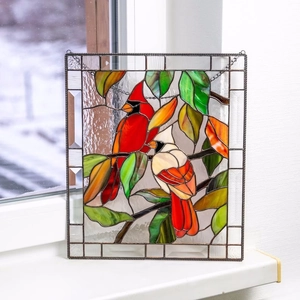 Detail of stained glass cardinal birds hanging on a snowy window background
