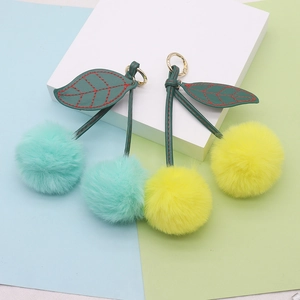 Close-up of plush cherry keychains in mint green and yellow with gold metal clasps