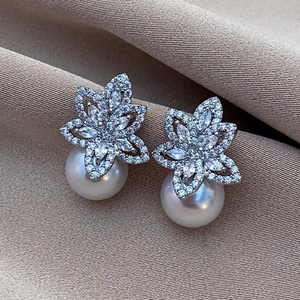 Macro shot of silver floral earrings featuring sparkling zircons and large white pearls