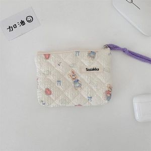 Close-up of quilted floral pouch with bunny prints and purple braided zipper pull