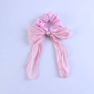 Detailed view of pink satin scrunchie featuring a large bow and central pearl accent