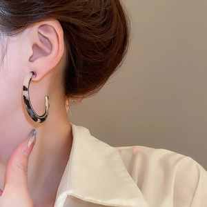 Detail view of retro tortoiseshell resin C-shaped hoop earrings worn by a model