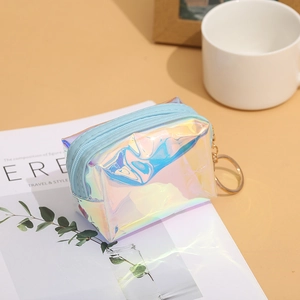 Close-up of holographic laser mini pouch with blue zipper and gold keychain on magazine