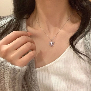 Close-up of snowflake pendant necklace with blue center stone on silver chain