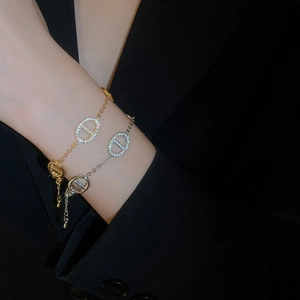 Detailed view of gold and silver plated link bracelets with zircon encrusted oval motifs