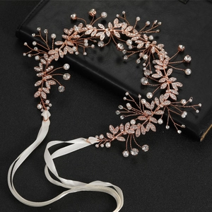 Detail of rose gold bridal headband with rhinestones and pearls on black leather