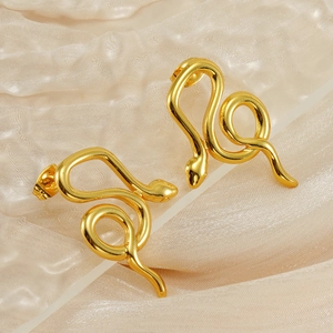 Élégantes boucles d'oreilles serpent en acier titane doré sur un fond en soie beige