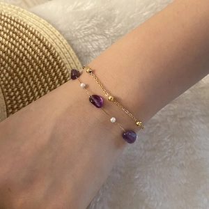 Detail of layered gold beaded bracelet with natural amethyst stones and white pearls