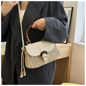 Detail of straw woven bag featuring floral embroidery and chic bamboo handle