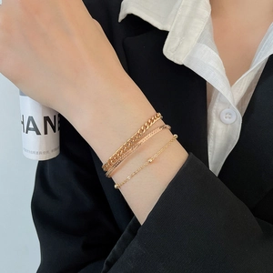 Detailed macro view of triple layered gold snake chain bracelets on a woman wrist
