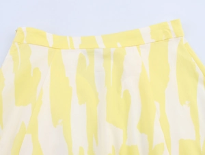 Detail view of high-waisted midi skirt with yellow abstract print and invisible zipper
