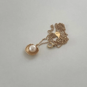 Close-up of S925 sterling silver stamp on golden shell pendant with pearl detail