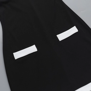 Detalle del vestido ajustado negro con bolsillos blancos en contraste y tejido de punto