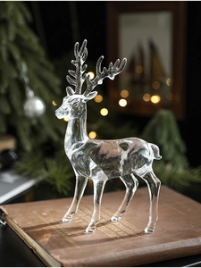 Macro shot of a clear acrylic reindeer ornament on a vintage book with festive lights