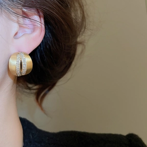 Close-up of 18K brushed gold C-shaped earrings with central cubic zirconia inlay on model