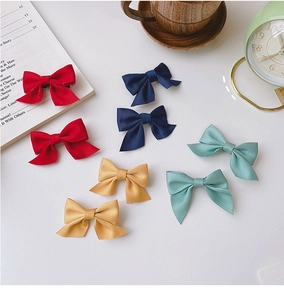 Flat lay of colorful satin bow hair clips set with vintage clock and prop books