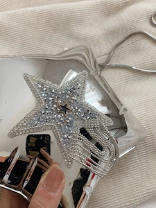Macro detail of star-shaped rhinestone brooch with long silver metallic tassels