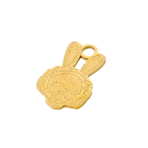 Macro shot of gold-plated skull pendant with rabbit ears and polished metal texture