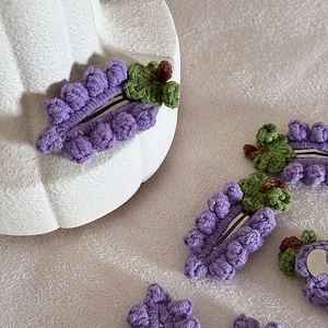 Fermagli per capelli a uva viola fatti a mano con dettaglio foglia su sfondo minimalista