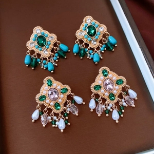 Detailed view of vintage baroque tassel earrings with emerald stones and teardrop pearls