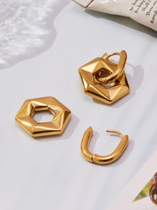 Macro detail of modular hollow hexagonal gold pendant and U-shaped stainless steel earring