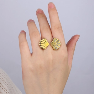 Détail d'une bague coquillage dorée avec strass portée au doigt pour vitrine de bijoux