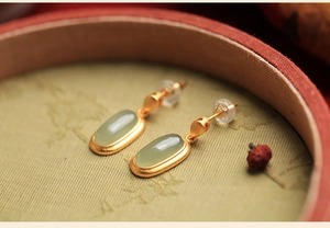 Close-up of gold enamel flower earrings with jade drop in a vintage jewelry box
