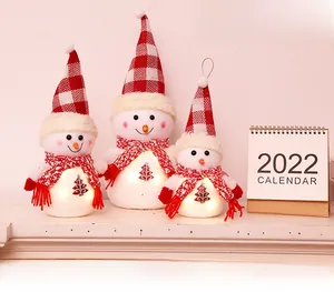 Detailed view of three glowing plush snowmen with red plaid hats and warm LED lights