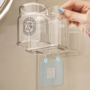 Wall-mounted transparent toothbrush holder with silver frame being installed on tile