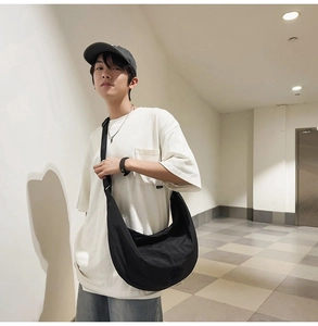 Mannequin masculin portant un sac bandoulière en nylon noir dans un couloir moderne