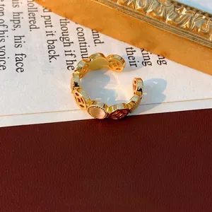 Bague dorée vintage avec pierres œil de chat roses et motif pièces sur des pages de livre