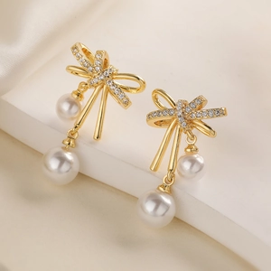 Exquisite gold-plated bow earrings with pearls and zircon on a minimalist display stand