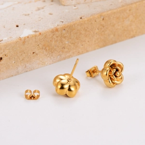 Elegant gold-tone stainless steel rose flower earrings on a textured stone surface