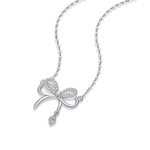 Macro shot of silver bow pendant featuring dense white zircon inlay and dangling diamond charm