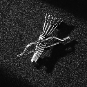 Close-up of vintage silver bow and arrow quiver brooch with black stones on black background