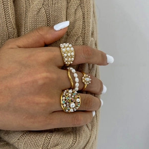 Gold stainless steel rings set with white pearls and colorful gemstones worn by a model